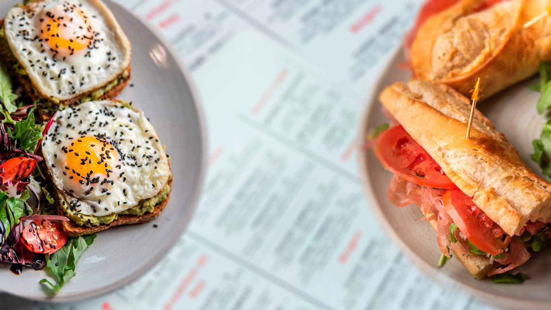 Avocado toast with sunny-side eggs and a sandwich on the table at Café Korzo